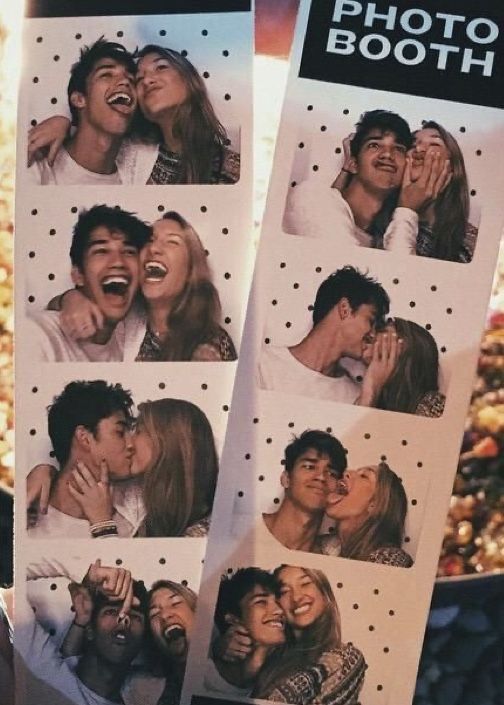 two people are kissing each other in front of a photo booth with pictures on it