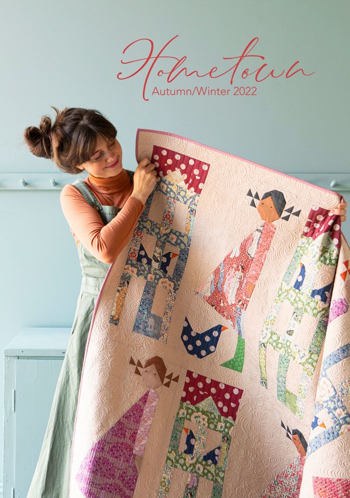 a woman is holding up a quilt