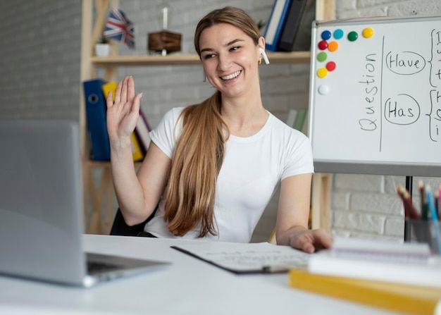 a woman sitting in front of a whiteboard and holding her hand up to the side