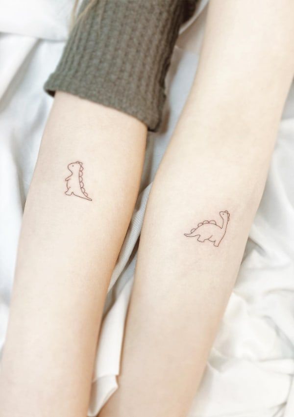 two people with tattoos on their arms and legs, one has a dinosaur tattoo on the other arm