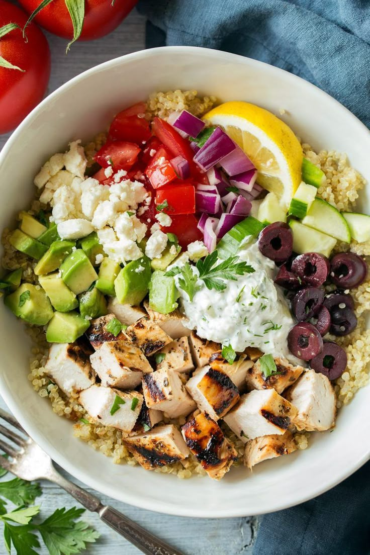 a white bowl filled with chicken, rice and veggies on top of a table