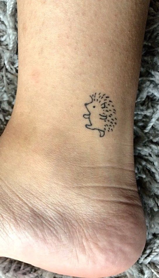 a small tattoo on the foot of a person with a hedgehog head in it