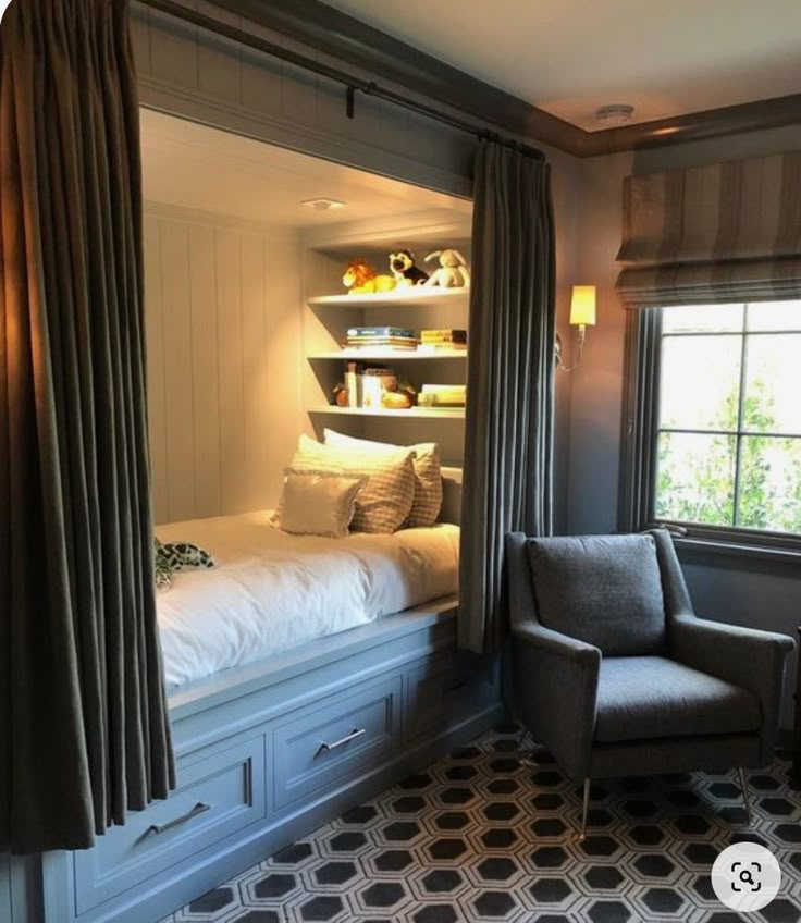 a chair sitting in front of a window next to a bed with built - in bookshelves