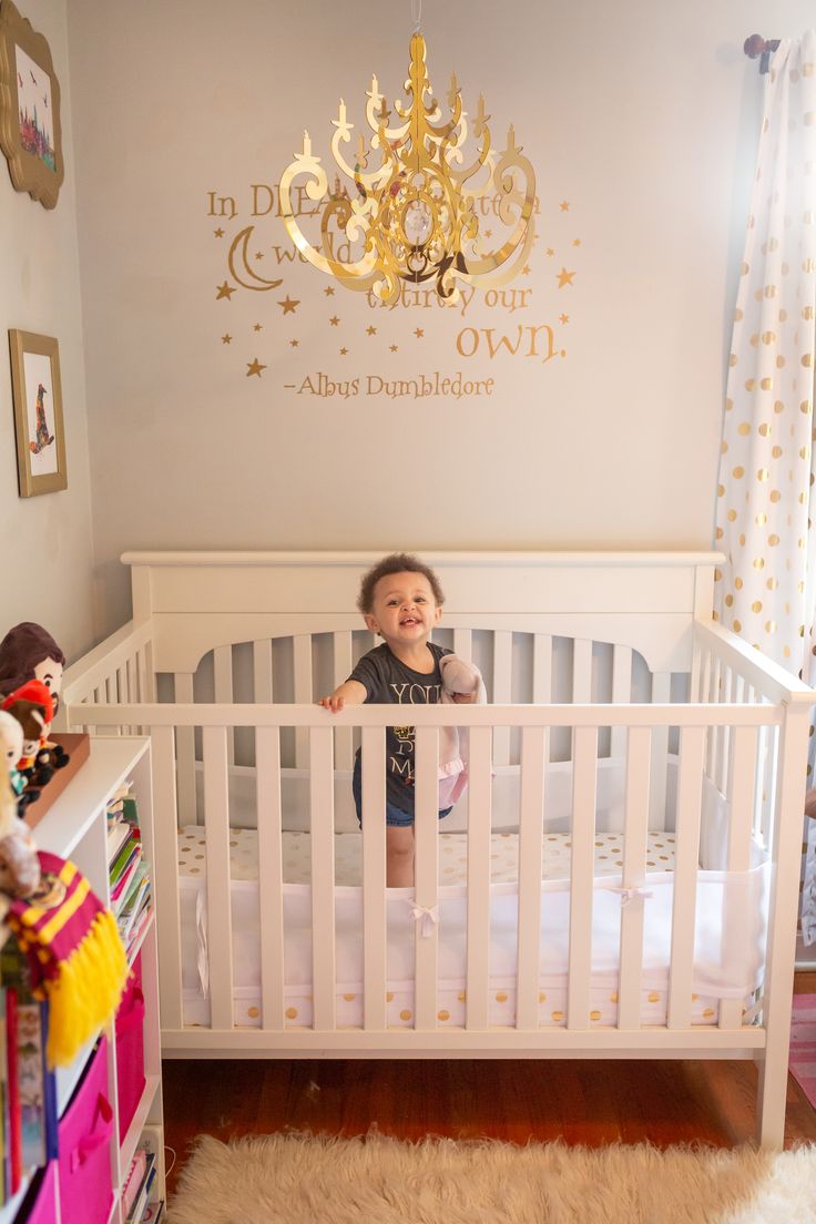 a small child in a white crib with a chandelier