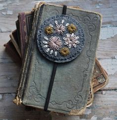 an old book with flowers on it sitting on top of a pile of other books