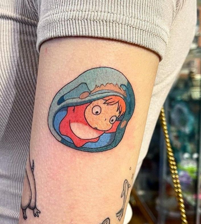 a woman's arm with a cartoon character tattoo on the left side of her body