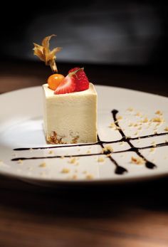 a piece of cake on a white plate with chocolate sauce and fruit garnish