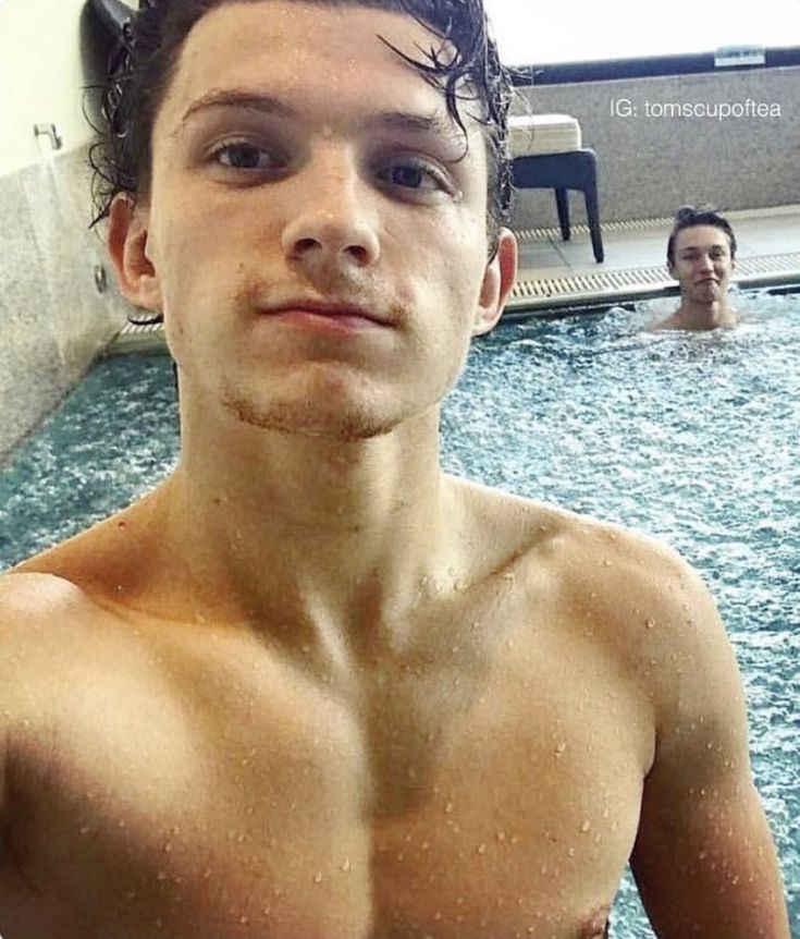 a man standing in a swimming pool with his shirt off and another person behind him