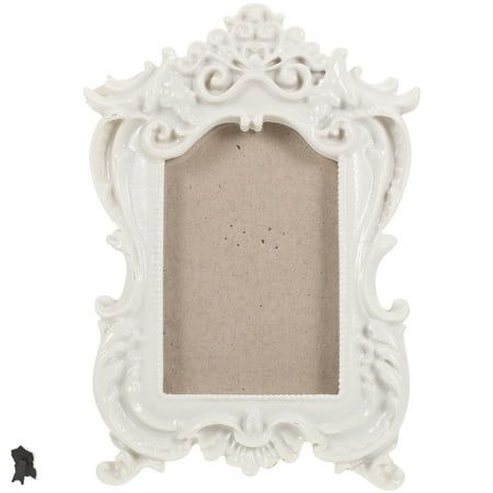 an ornate white frame with a small black object next to it on a white background