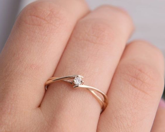 a woman's hand with a diamond ring on top of her finger, showing the side view