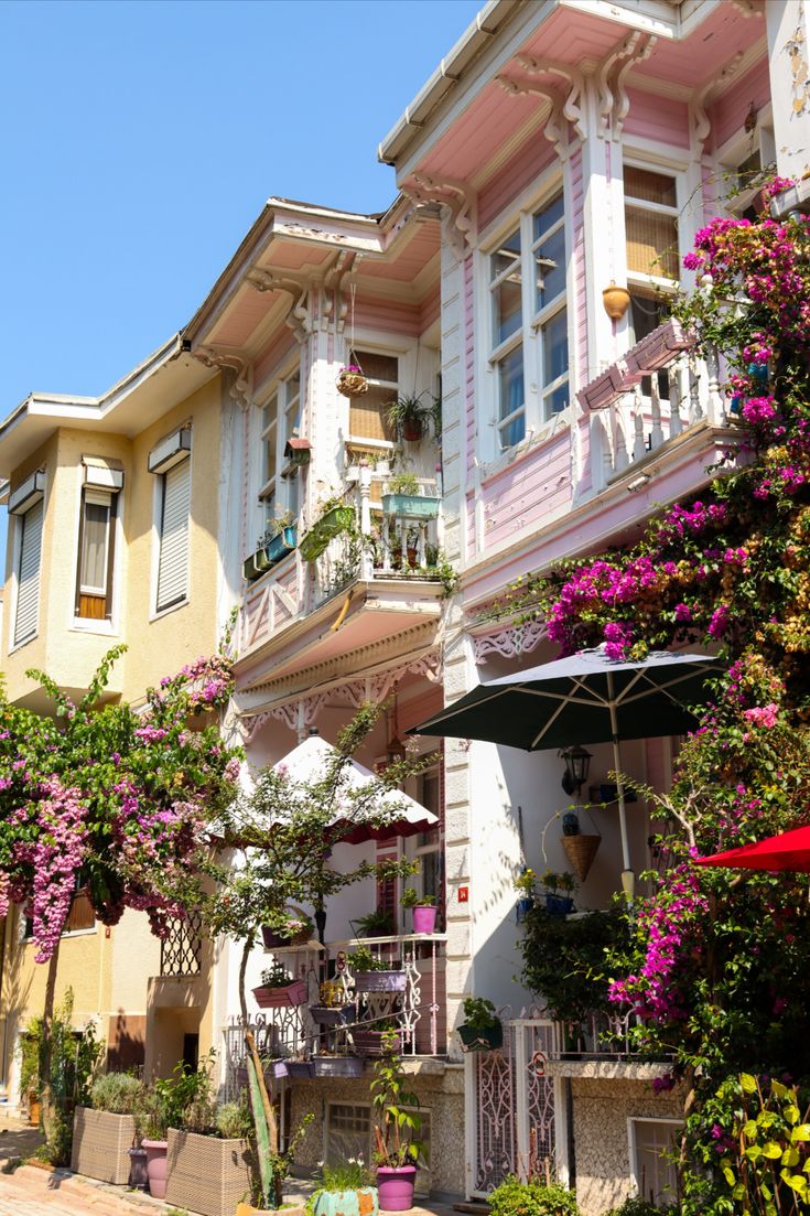 a row of multi - story buildings with pink flowers on the balconies and balconyes