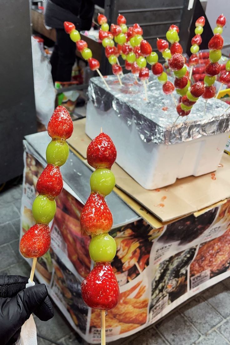 a bunch of fruit on sticks in front of a box