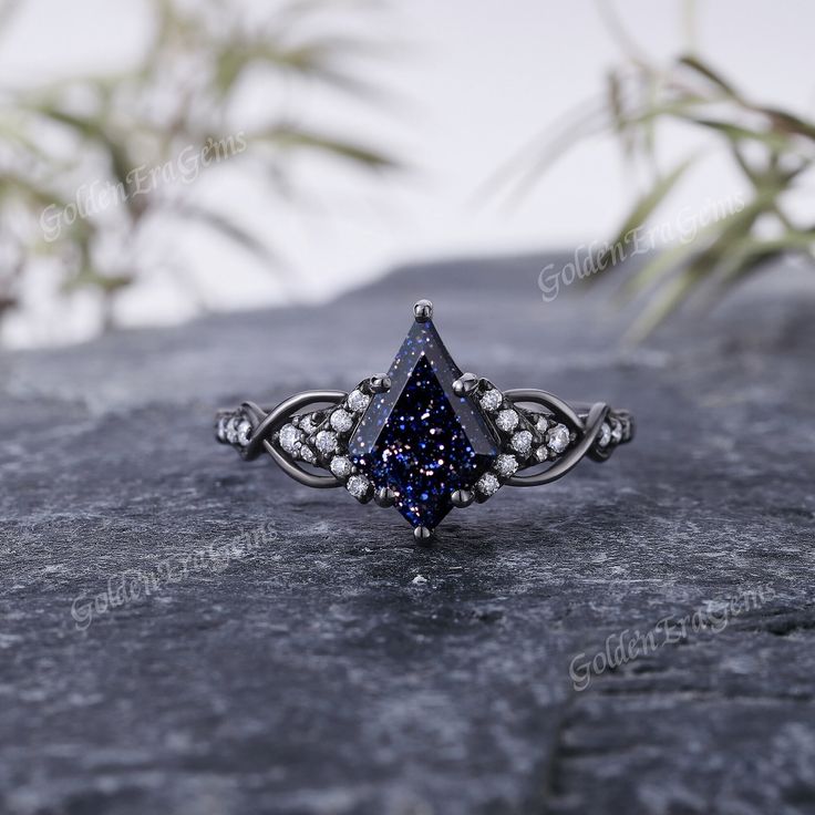 a blue diamond ring sitting on top of a rock