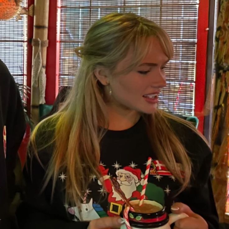 a woman holding a coffee mug in front of a man wearing a santa clause shirt