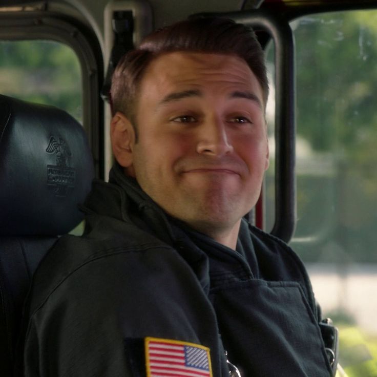 a man sitting in the back seat of a bus with an american flag patch on his chest