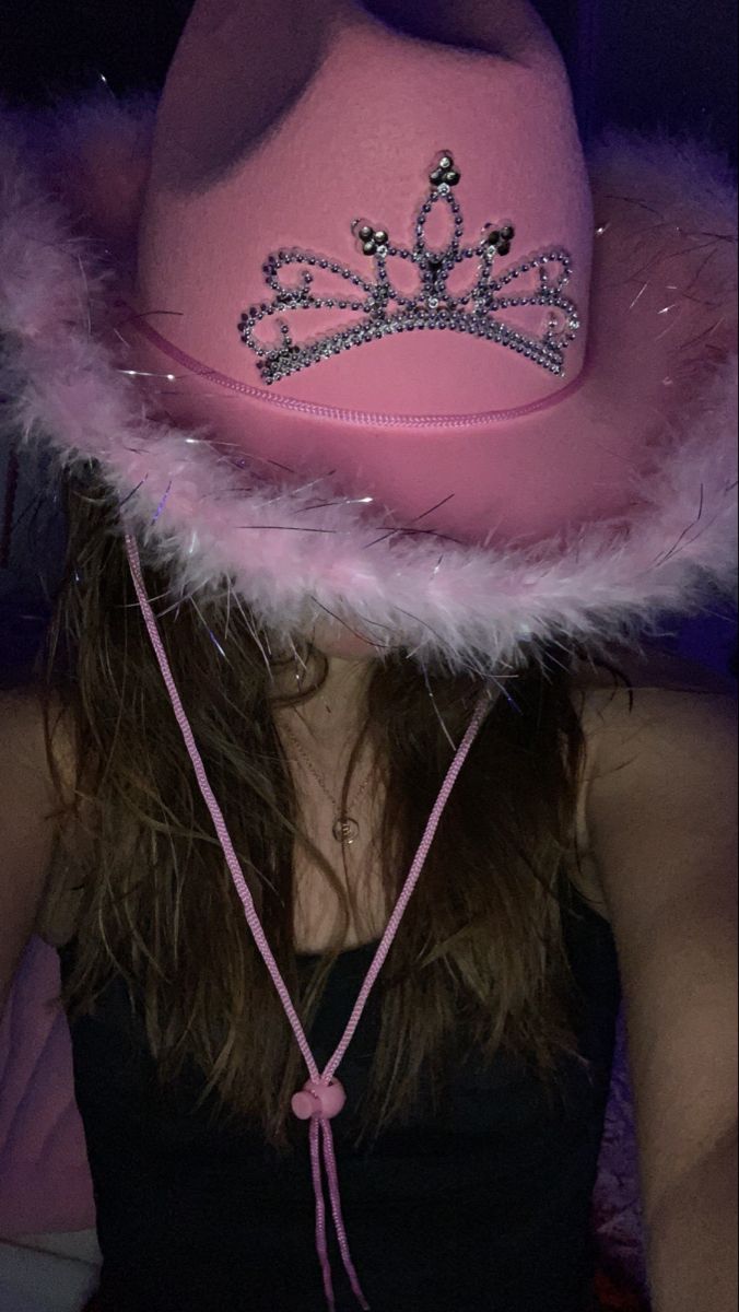 a woman wearing a pink hat with a tiara on it's brim