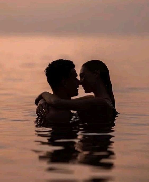 two people are in the water with their arms around each other and one is kissing