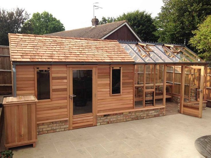 a small wooden building sitting in the middle of a yard with lots of windows on top of it