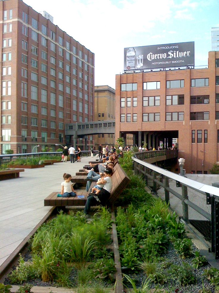 people are sitting on benches in the middle of an urban area with tall buildings behind them