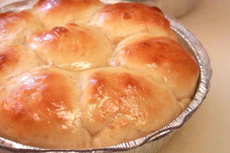 a pan filled with bread sitting on top of a counter next to a bowl full of rolls