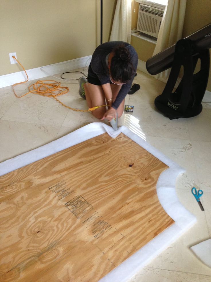 a man that is kneeling down on the floor with some wood in front of him