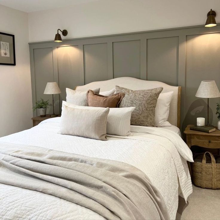 a bed with white linens and pillows in a small room next to two lamps on either side of the headboard