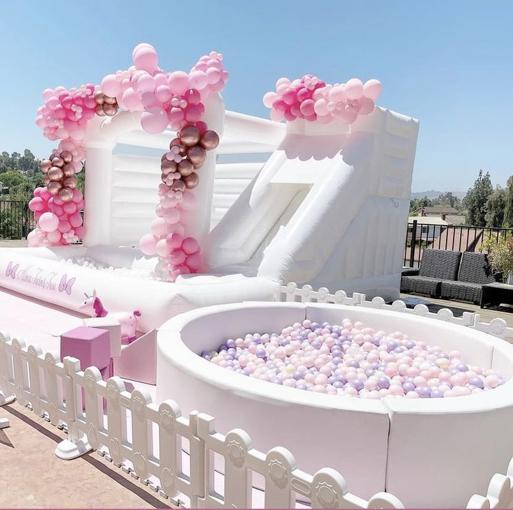 an inflatable pool with pink and white balloons on the top, surrounded by other decorations