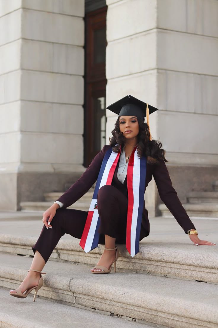 a woman sitting on steps wearing a graduation cap and gown