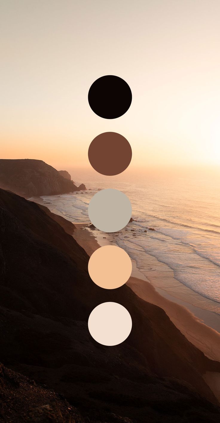 the sun is setting over the ocean and there are five circles hanging from the ceiling