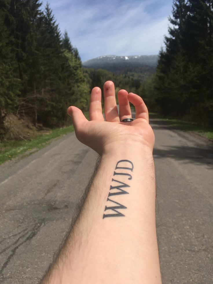 a person holding their arm with the word down written on it and trees in the background