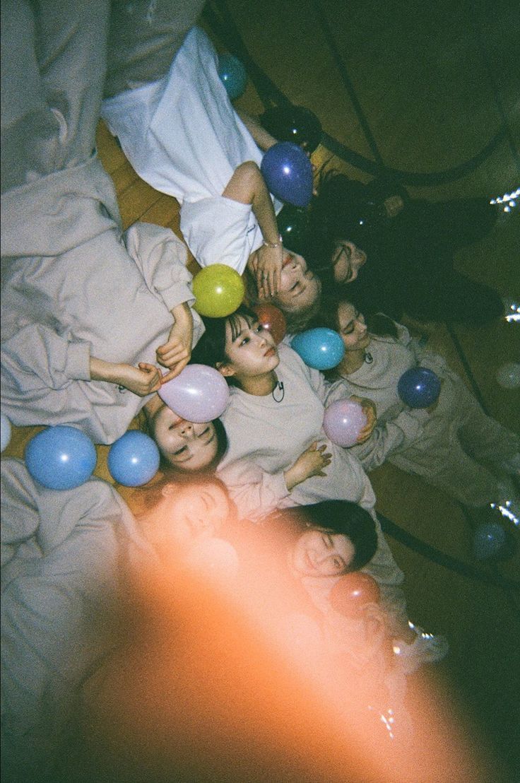 a group of people laying on top of a bed with balloons