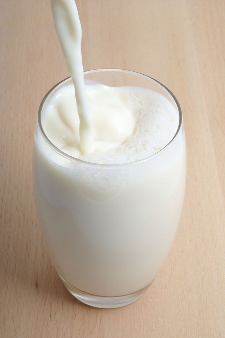 a glass filled with milk sitting on top of a wooden table