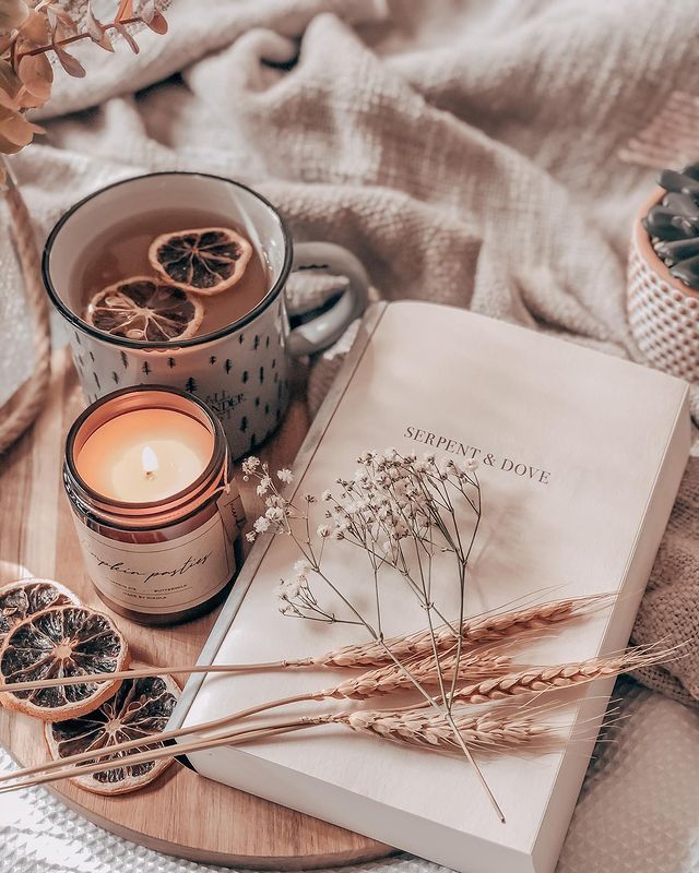 an open book and some dried oranges on a table with a cup of tea