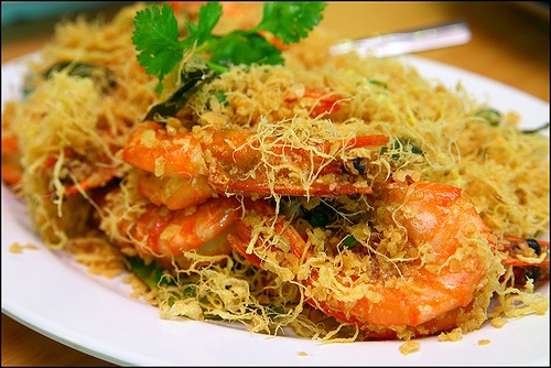 a white plate topped with pasta and shrimp covered in parmesan sprinkles