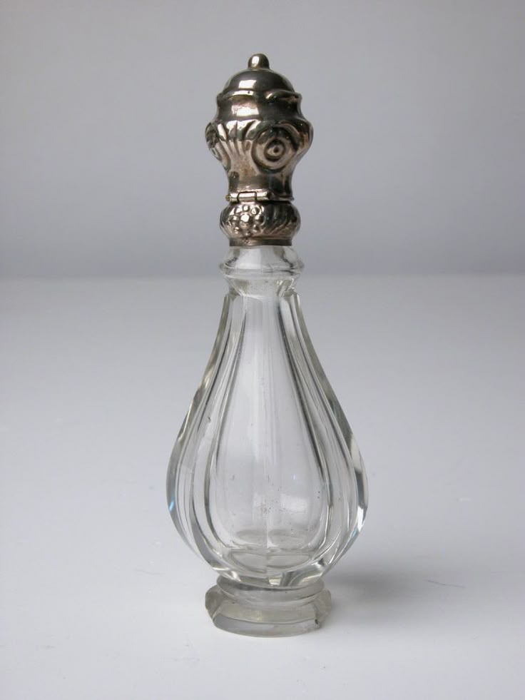 a glass bottle with a silver top on a white surface