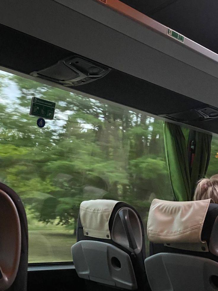 the interior of a bus with seats and trees in the background