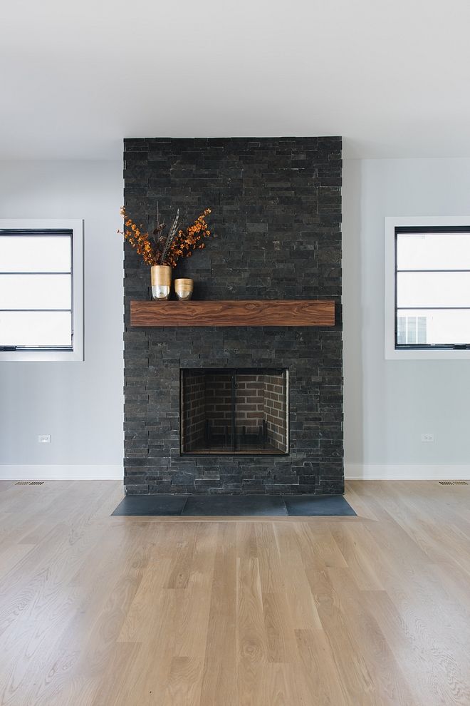 an empty living room with wood floors and a brick fireplace