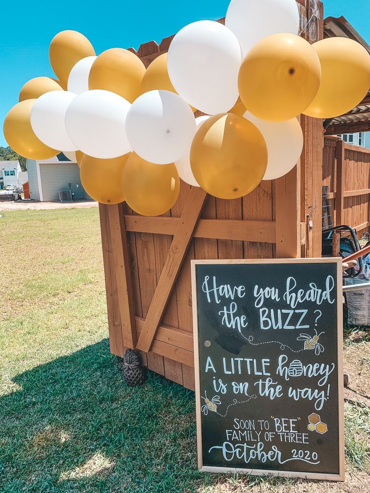 a sign that is in the grass with balloons attached to it's back side