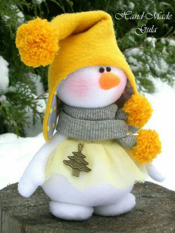 a stuffed snowman wearing a yellow hat and scarf on top of a tree stump