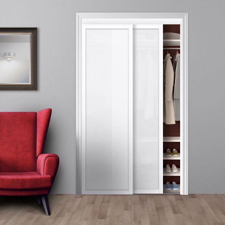 a red chair sitting in front of a closet with white doors and shoes on the floor