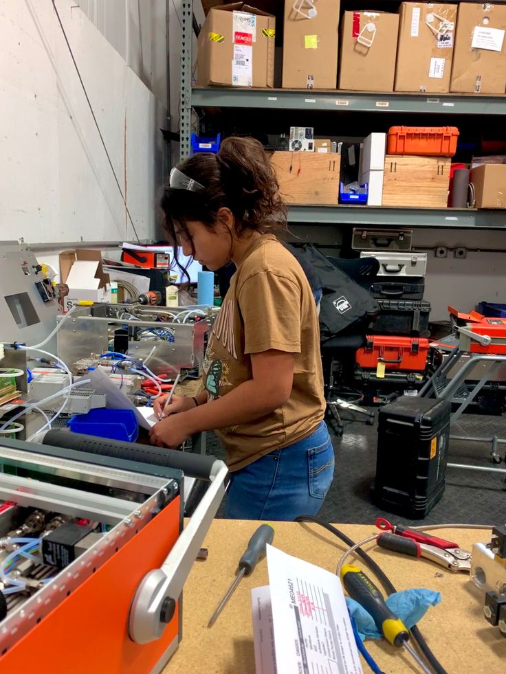 a woman is working on an assembly line in a factory with boxes and other tools