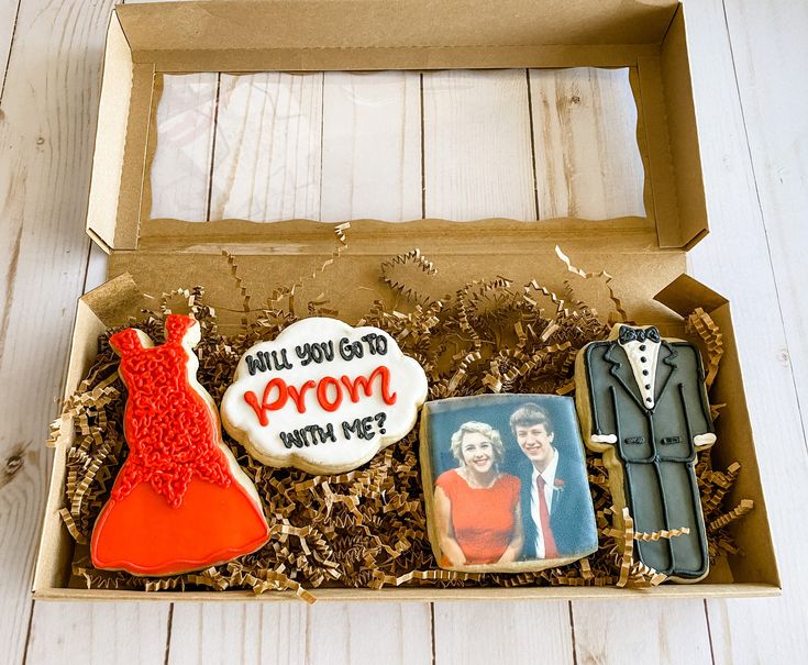 an open box with decorated cookies in the shape of women's dresses and men's suits