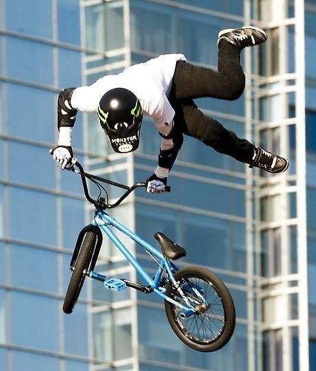 a man flying through the air while riding a blue bike in front of a tall building