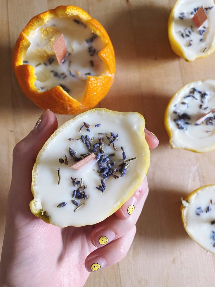 a person holding an orange with lavender sprinkles on it next to other pieces of fruit