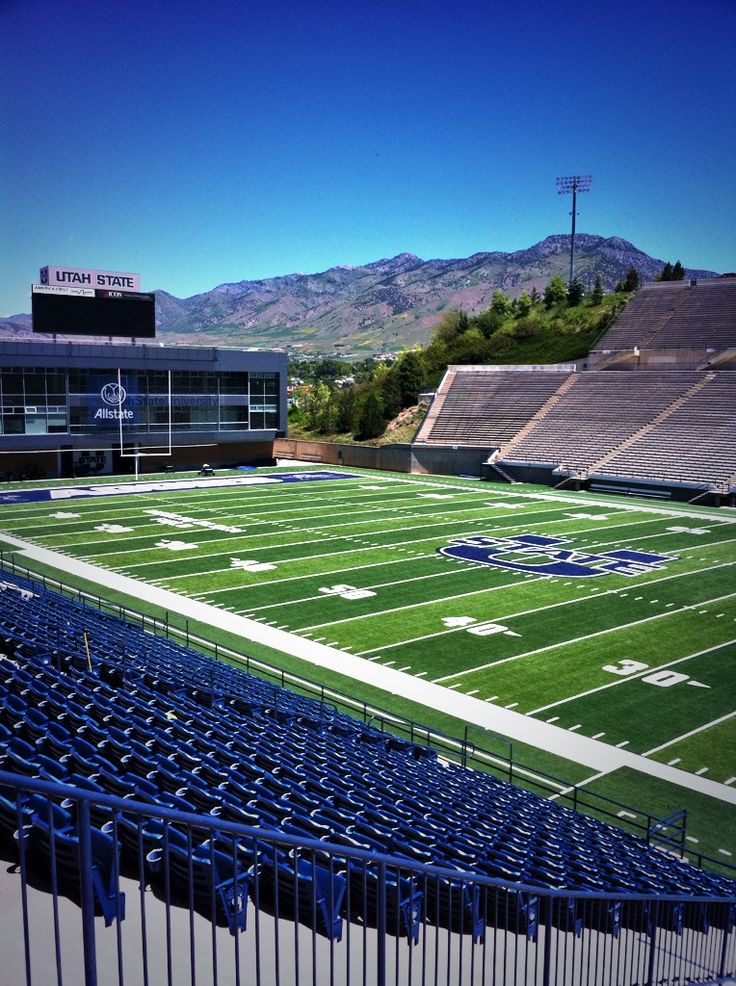 an empty football stadium with the mountains in the backgrouund and blue seats