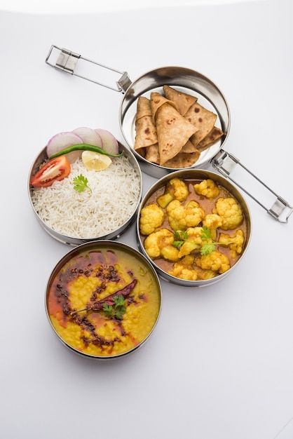 four bowls filled with different types of food on top of a white tablecloth covered surface