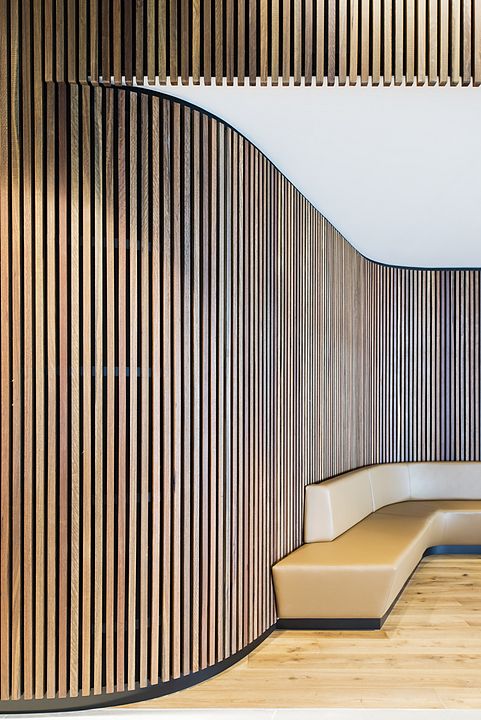 an empty room with wooden slats on the wall and leather benches in front of it