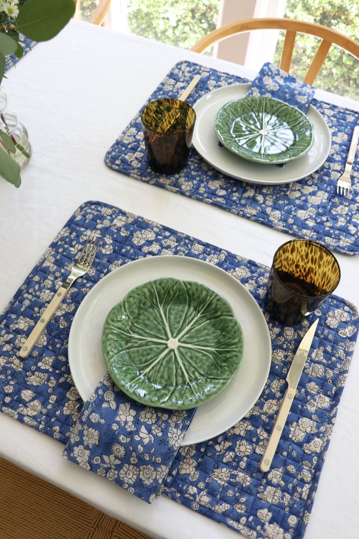 two place mats with plates and silverware on top of them, sitting on a table