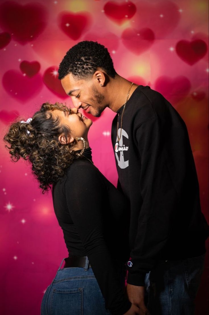 a man and woman kissing in front of hearts