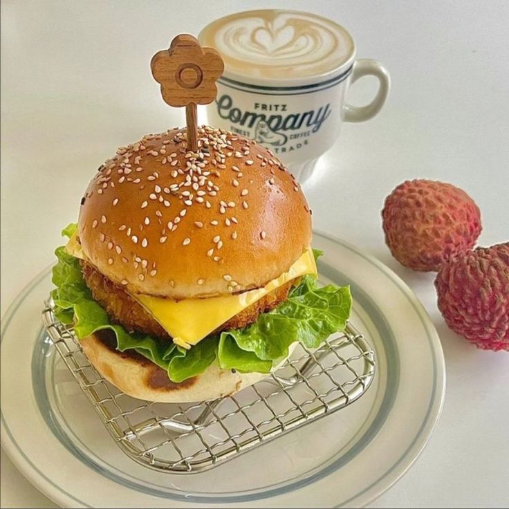 a cheeseburger with lettuce and tomato on a plate next to a cup of coffee